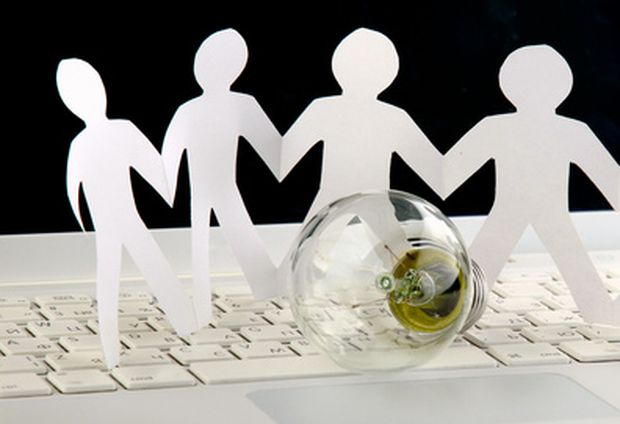 Light bulb and computer keyboard with paper people.